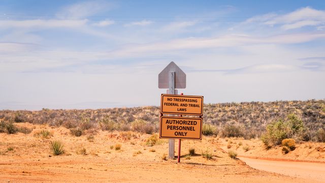 a no trespassing sign under the expansive blue sky