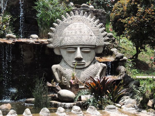 Stone sculpture inspired by Pre-Columbian design in a lush Bogotá garden setting