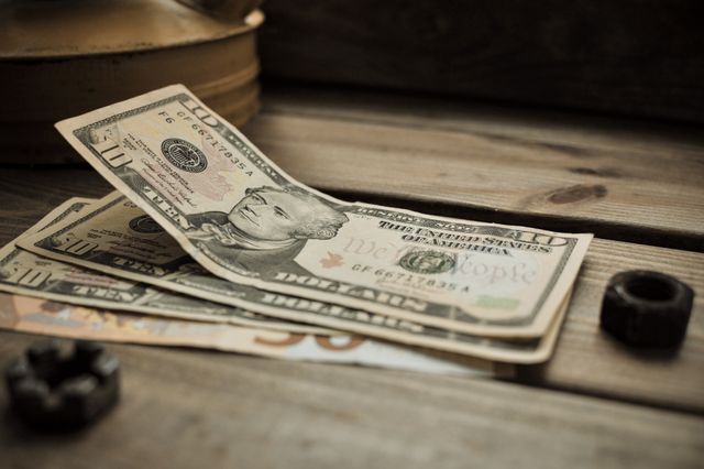 A stack of US dollar bills on a rustic wooden table close-up view