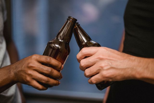 Friends toasting with beer bottles in the microbrewery.