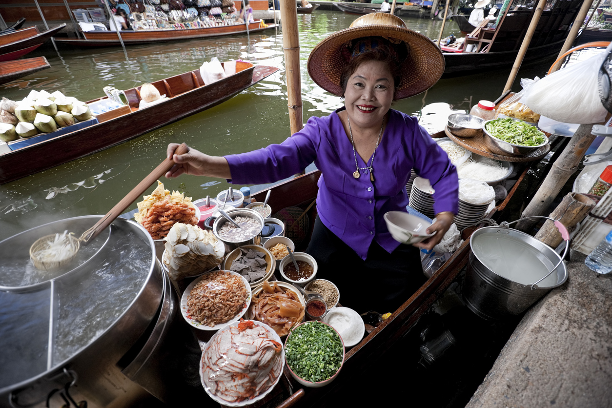 Food vendor at the Damnoen Saduak Floating Market preparing Thai style noodles, Thailand. Bangkok on a budget