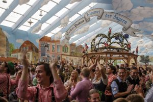 Inside the Hacker Festzelt (Himmel der Bayern) at Oktoberfest on Theresienwiese with its lovely decoration of the roof and the surrounding walls, unidentified people are celebrating in the tent