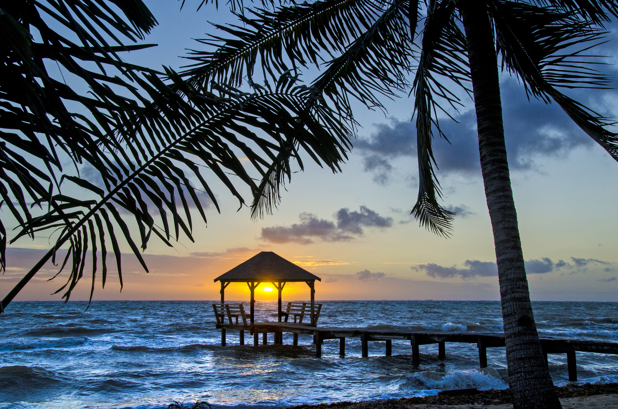 A palapa at sunrise on the end of a pier in Placencia, Belize, best adventure trips for couples