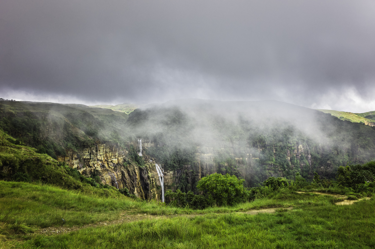 Storm clouds gather over the Khasi Hills with waterfall and high granite rock slopes and deep gorges near Cherrapunjee. Meghalaya, India.