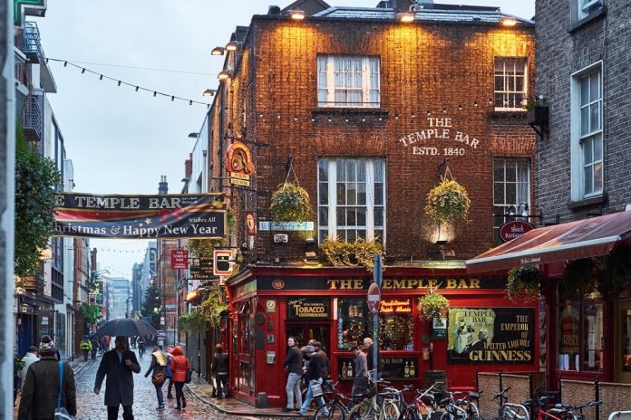 Pedestrians walking around street in Temple Bar during rainy evening. The area is the heart of tourism in the city.