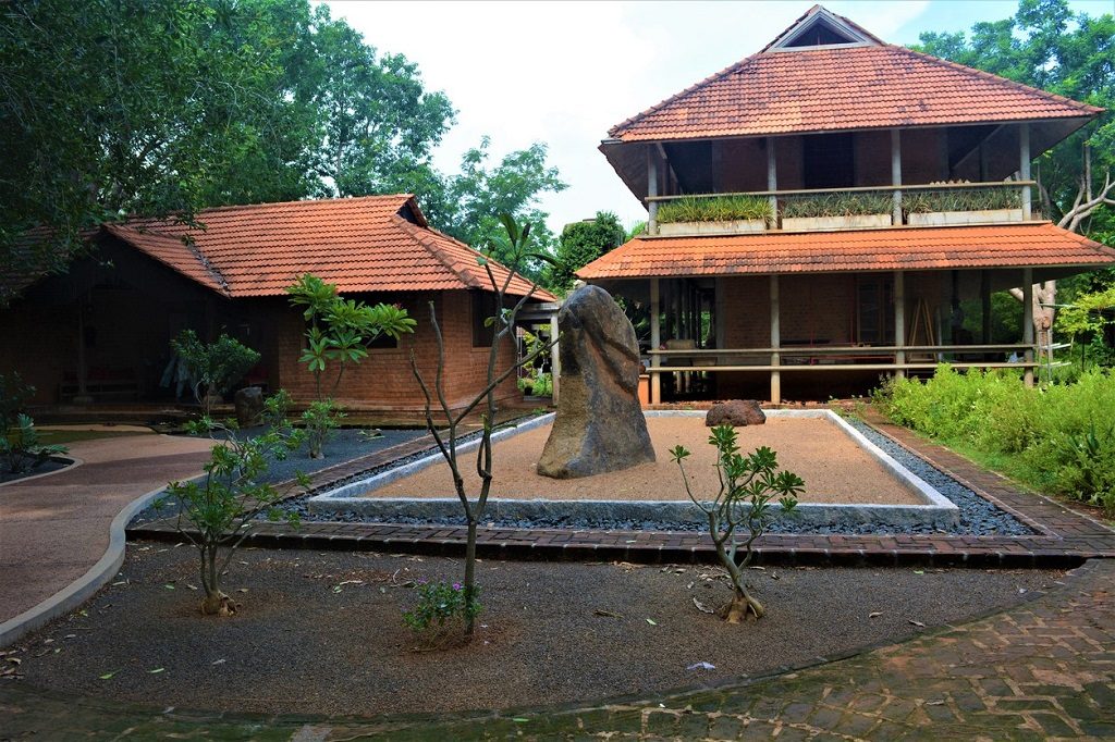 Japanese styled architecture and a standing stone in front of it at AUROVILLE, INDIA