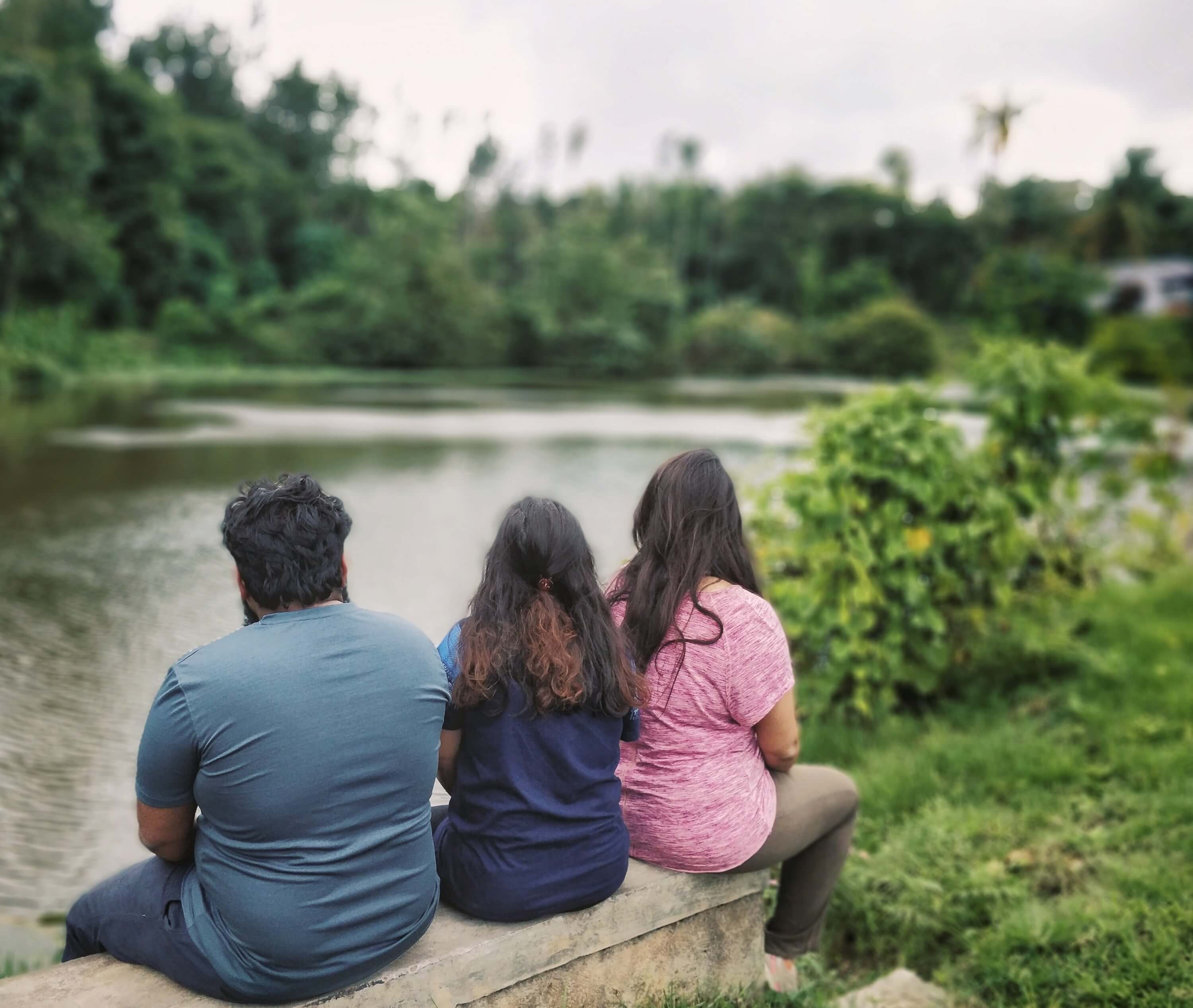 Three people sitting by a beautiful lake side - Malanad Calling