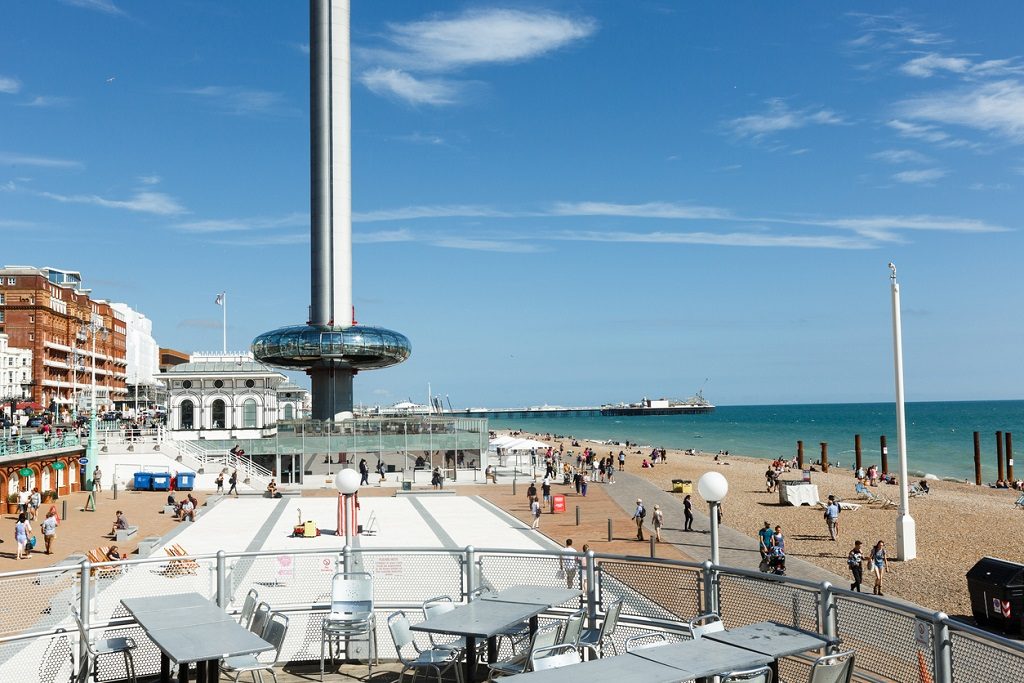 People admire walking on Brighton costline, view of English channel, tower i360