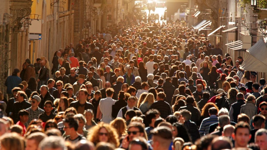 Large group of people crowding Rome's downtown streets in a sunny day.