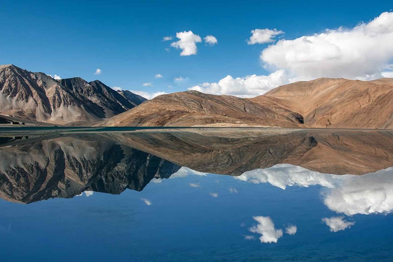 Cold Desert of India: Complete Travel Guide to Ladakh’s Unique High-Altitude Desert 13 Pangong Lake reflecting surrounding rugged mountains under a clear blue sky in Ladakh