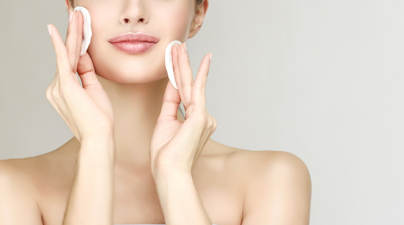 model is cleaning her face skin by cotton pads, for skin care during summer travel