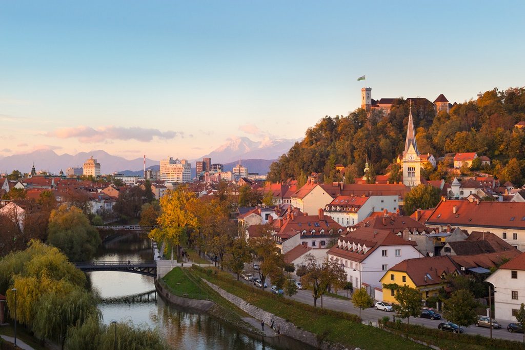 Cityscape of the Slovenian capital Ljubljana at sunset. Ljubljana castle on hill above town. River Ljubljanica running trough city center. Karavanke mountains in background, Yugoslavia