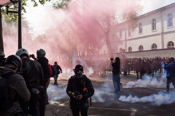 A pink smoke bomb and tears gas during the protest of may 1st 2017, in Paris. A lot of protesters and journalists. | Source: Unsplash A pink smoke bomb and tears gas during the protest of may 1st 2017, in Paris. A lot of protesters and journalists. | Source: Unsplash