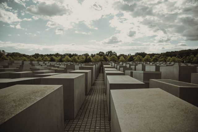 view of the Holocaust Memorial in Berlin under a dramatic and cloudy sky.