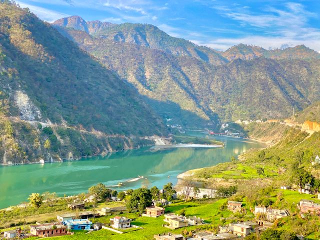Picturesque view of a serene village nestled by a river in a mountain valley,