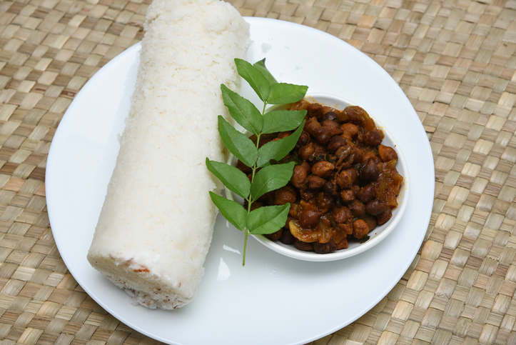 Popular South Indian breakfast puttu / pittu made of steamed rice flour and coconut in the bamboo mould with spicy beef or mutton meat curry , Kerala, India. Bamboo puttu. Sri lankan food