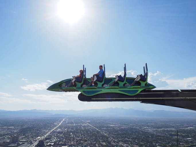 Tourists sit inside a cart of the thrill ride "X-Scream" on top of the Las Vegas Stratosphere tower (1149 ft/350m), the tallest freestanding observation tower of the US - things to do in Las Vegas