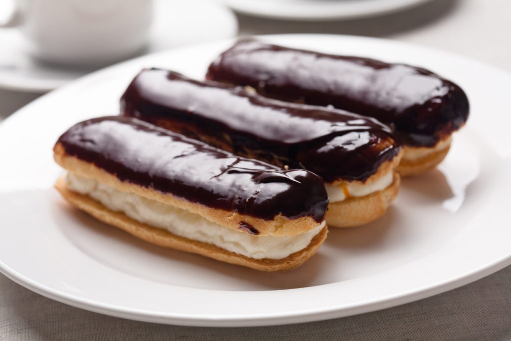 Chocolate eclairs on plate on white background