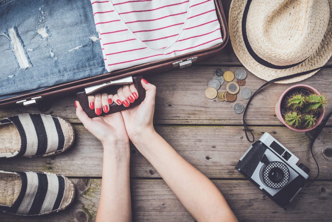 Travel preparations concept with suitcase, clothes and accessories on an old wooden table. Zero waste travel