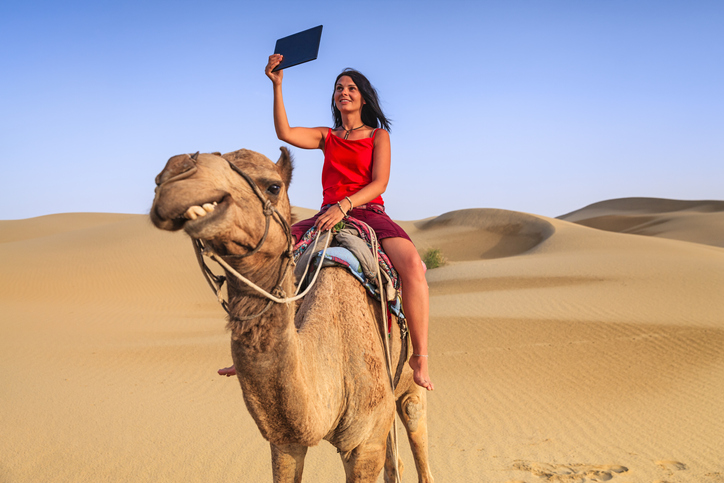 Young female tourist taking selfie on a camel, Rajasthan, India