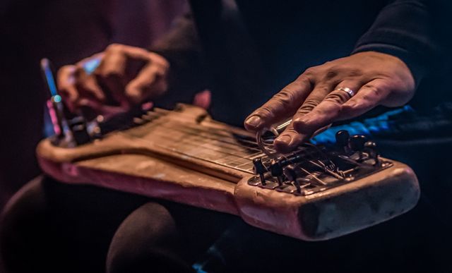 musician playing a vintage lap steel guitar with a slide and ring