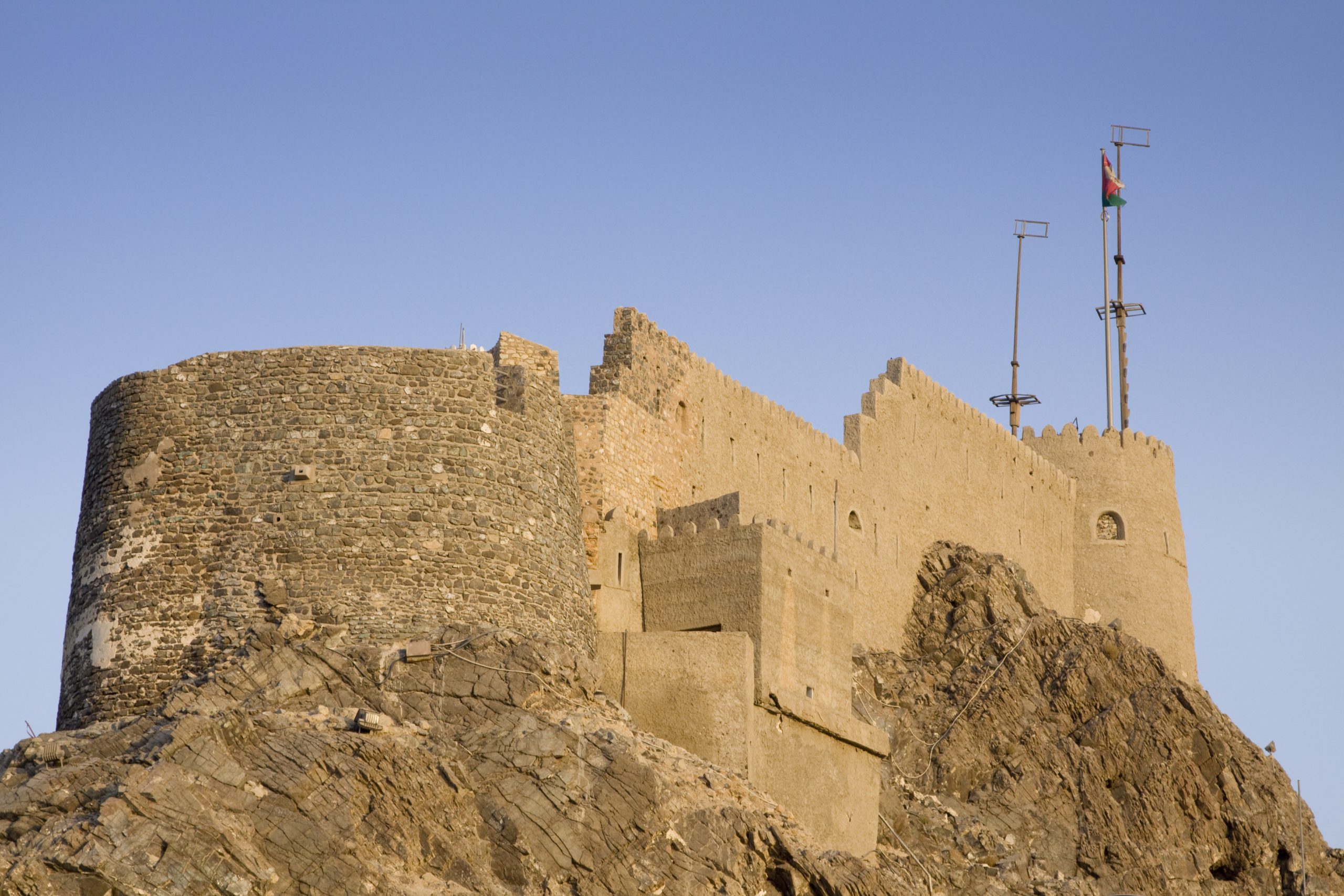 Mutrah fort on the top of a hill overlooking the harbour of Muscat, Oman just before sunset."