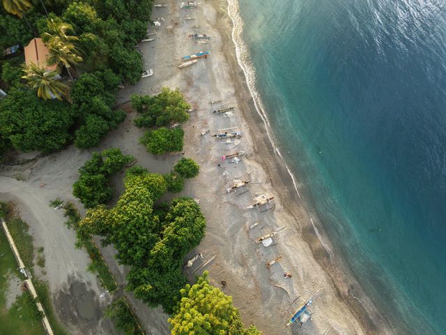 A stunning aerial view of a beach in Timor-Leste with fishing boats and lush greenery
