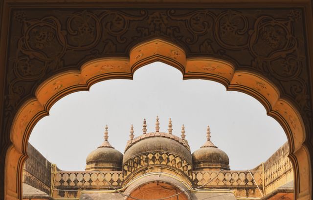 Decorative archway framing domes of a historic palace showcasing symmetry and ornate architectural detail.