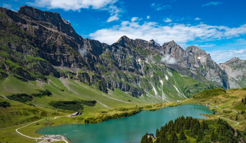 A stunning aerial view of the Swiss Alps featuring a serene blue lake and lush green landscape