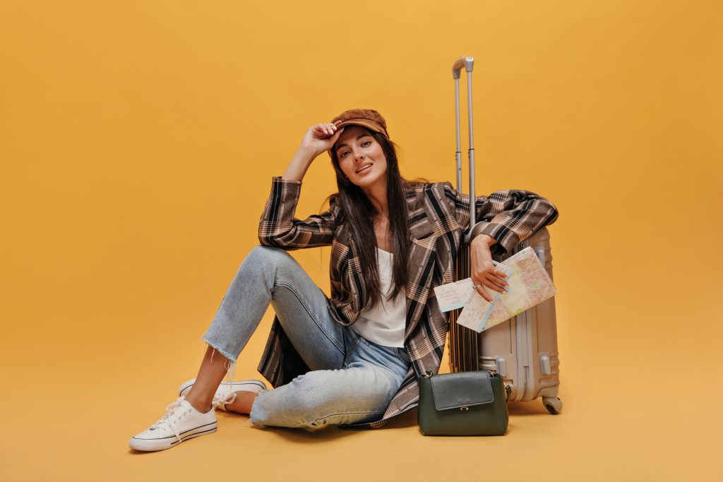 https://d2rdhxfof4qmbb.cloudfront.net/wp-content/uploads/2023/03/brunette-young-woman-beret-white-tee-coat-jeans-looks-into-camera-smiles-stylish-girl-sits-floor-leans-suitcase-holds-map-isolated-yellow-background-1024x683.jpg