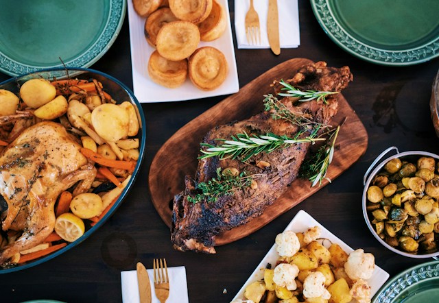 Roasted duck with potatoes, red cabbage and sauce, a festive meal on a dark rustic wooden table.