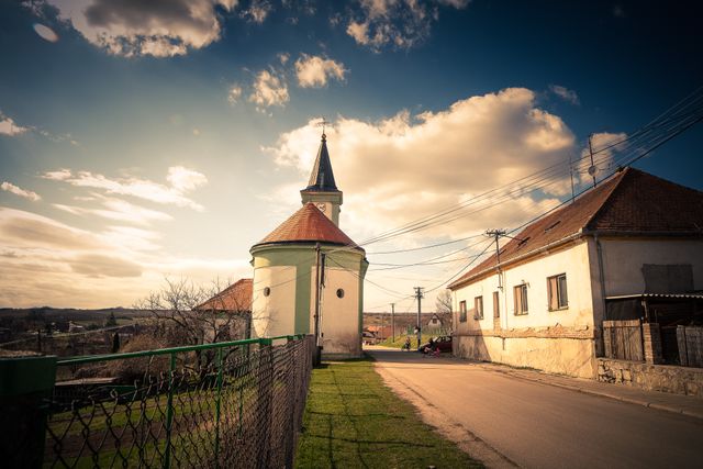 Idyllic village scene with a church and houses under a warm sunset sky.